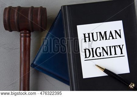 Human Dignity - Words On A White Sheet With Leather Notebooks, A Judge's Hammer And A Pen