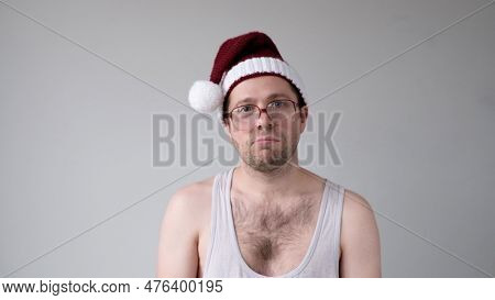 The Sad And Sorrowful European Young Man In A New Years Hat Looks Gloomily Into The Camera. Disappoi