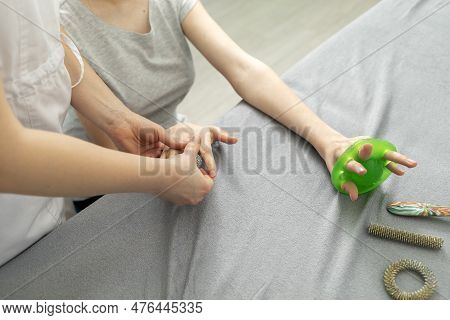 Unrecognizable Doctor Neurologist Stretches Fingers Of Female Young Girl With Disability. Physical T
