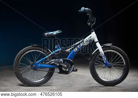 Blue Used Children Bicycle Stels Pilot 170 16 Inch Tires In Dark Room Background.