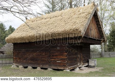 Wooden Cottage With Straw, Thatched Roof In Meadow, Open Air. Bungalow Construction In Rural Eastern