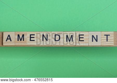 Word Amendment Made Of Small Gray Wooden Letters On A Green Paper Background
