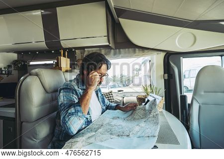 One Man Reading Road Map Inside A Modern Camper Van Motorhome To Choose Best Trip. Traveler People W