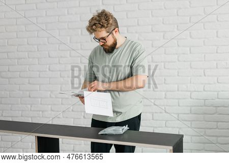 Young Attractive Man Assembles Furniture - Handwerker And Interior Objects Concept
