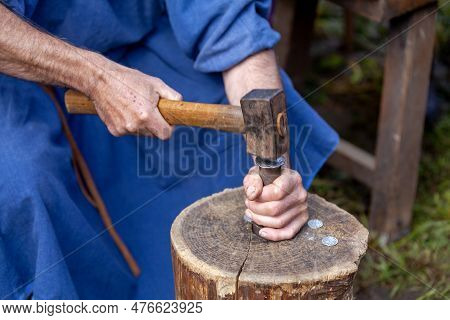 Medieval Minter Minting A Coin With His Hammer On A Log.