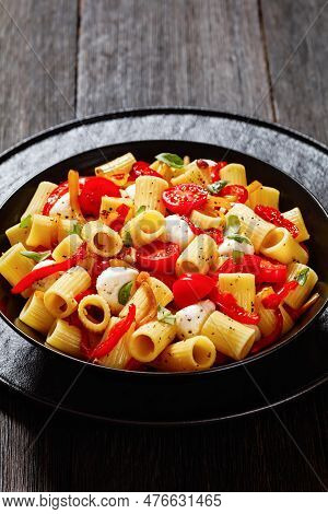 Roasted Pepper Tomato Mozzarella Pasta Salad In Black Bowl On Dark Oak Wood Table, Vertical View, Cl