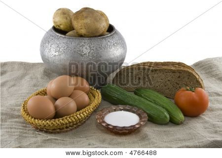 Still-life From Vegetarian Food. Fresh Cucumbers, Eggs Lying In A Wattled Small Basket, A Ripe Tomat