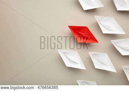 Leadership Concept. Red Leader Paper Ship Leading Among White On Grey Background. Space For Text. To