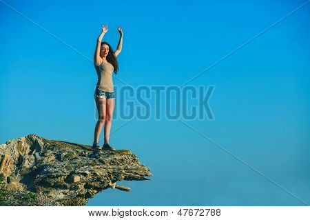 donna alta acrofobia sta in cima a bordo di una scogliera di roccia ed è