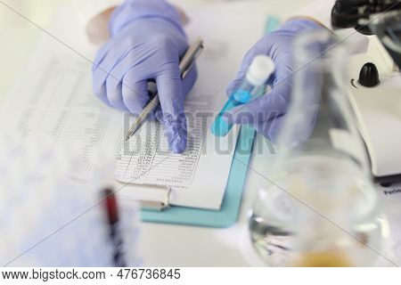 Scientist Compares Results Of Research To Data In Investigation Paper. Woman In Rubber Glows Holds G