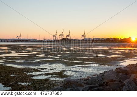 Tauranga March 11 2011; Editorial-distant Port Cranes And Containers Stacked At Sulphur Point As Sun