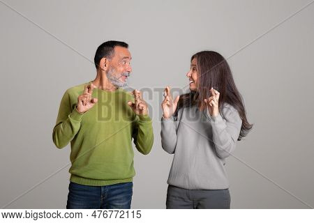 Positive Caucasian Aged Husband And Wife Crossed Fingers Dream Of Victory, Make A Wish