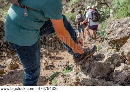 Elderly Caucasian Active Man In Mountain Footpath Stops To Tie His Shoe Laces - Adventure Is Ageless