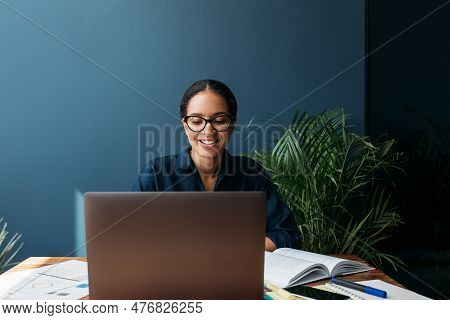 Young Female Entrepreneur In Thought Sitting On The Floor In The Kitchen With A Laptop On Her Legs