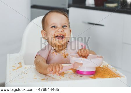 Happy Cheerful Messy Baby 9 Months Old Sits In A Highchair And Eats Lure Vegetable Puree Soup, The C