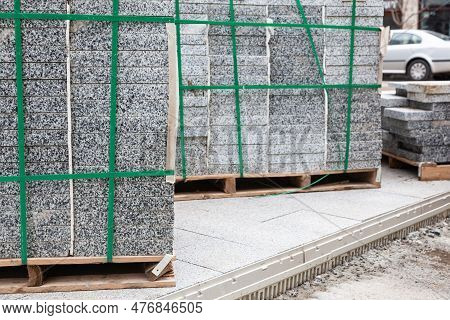 Packs Of New Paving Granite Tiles Stacked On Pallets For Laying On The Road.