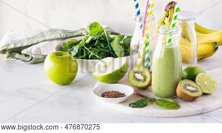 A Green Smoothie Surrounded By Ingredients Used To Make It.