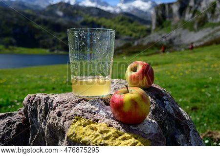 Glass Of Natural Asturian Cider Made From fermented Apples With View On Covadonga Lake And Tops Of P
