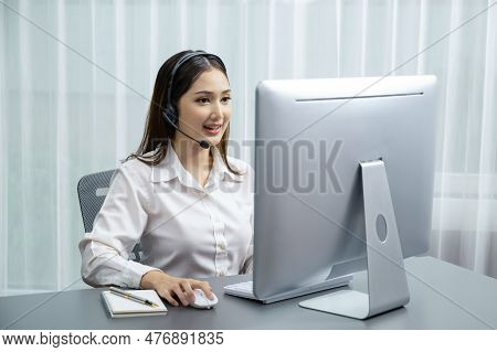 Asian Call Center With Headset And Microphone Working On Her Laptop. Female Operator Provide Excepti
