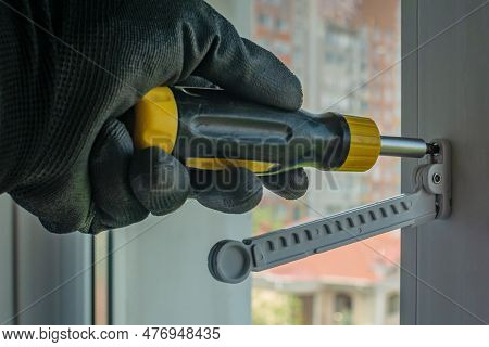 Male Using Screwdriver Tightens Screw That Fixes Plastic Window Opening Limiter Close-up Of Gloved H