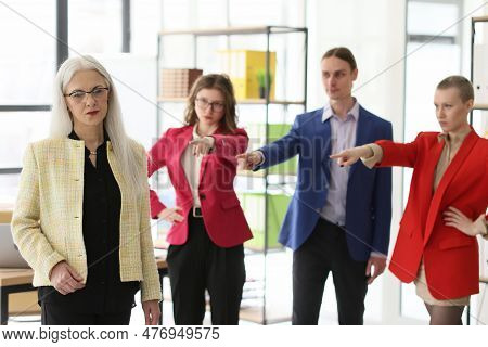 Disappointed Employees Point Fingers To Mature Staff Member Standing In Company Office. Angry Collea