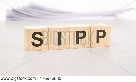 Sipp Text Written On Wood Blocks, Stack Of White Sheets In The Background