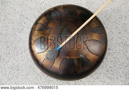 Steel Tongue Drum And Soft Mallet On Grey Table, Top View. Percussion Musical Instrument