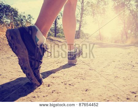  an athletic pair of legs running or jogging on a path during sunrise or sunset toned with a retro vintage instagram filter effect app or action 