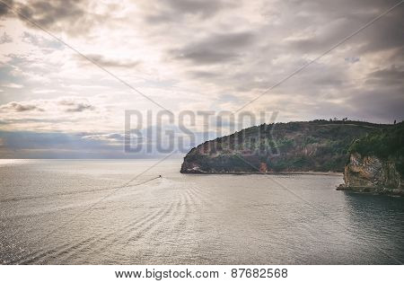 The View Over The Adriatic Sea Coast, The Sun Rays Coming Through The Cloudy Sky And A Ship Sailing