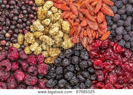 background of healthy dried superfruit berries - blueberry, mulberry, cherry, goji, elderberry, chokeberry, and cranberry