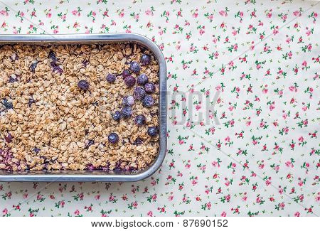 Oat Granola With Fresh Berries In A Silver Baking Dish Over A Flower Patterned Table Cloth