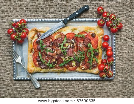 Ristic Meat Square Pizza With Cherry Tomatoes And Arugula Over A Sackcloth Surface