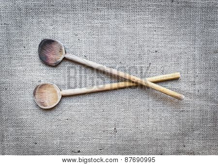 Two Rustic Wood Cooking Spoons Over A Sackcloth Surface