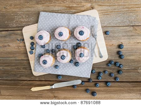 Whole Garin Cupcakes With Raspberry Cheese Cream And Forest Berries Over A Rough Wooden Surface