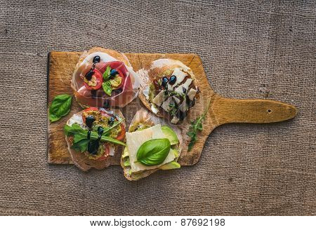 Antipasti Brusquetta Set On A Rustic Wooden Board Over A Sackcloth Surface