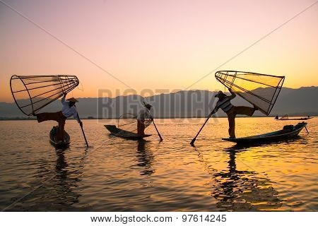 Three fishermen catches fish for food in sunrise in Inle Lake, Myanmar