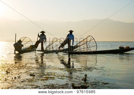 Three fishermen catches fish for food in sunrise in Inle Lake, Myanmar