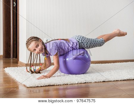 smiling girl with african braids on the ball for fittnes at home