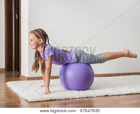 smiling girl with african braids on the ball for fittnes at home