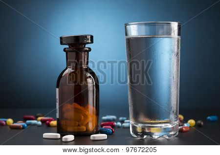 Medicine pills bottle and glass of drink water