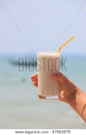 Female Hand Holding Milk Shake With Tropical Sea View Background