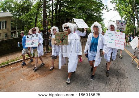 ATLANTA, GA - APRIL 22:   A group of women dressed like Albert Einstein hold up signs as they walk in the Atlanta  March for Science near Candler Park on Earth Day in Atlanta, GA on April 22 2017.