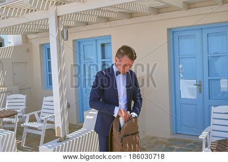 SANTORINI, GREECE - AUGUST 05, 2015: handsome bridegroom fill back pack on Santorini