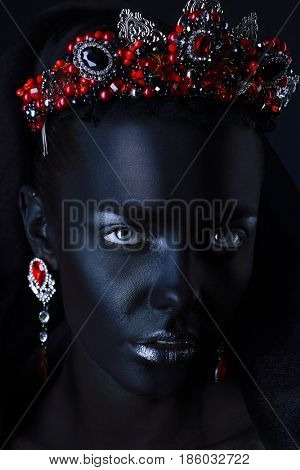 Jewelry industry. Fashion portrait of a beautiful young woman with perfect black skin wearing diadem with rubies and other precious stones. Jewelry and bijouterie. Body painting project.