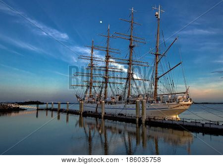 Japanese four masted sailing ship  in sunset-time against the background of bright blue sky and white cloud.