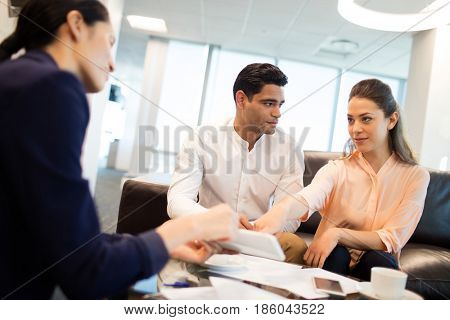 Young business people discussing over documets sitting on sofa at office