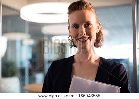 Portrait of smiling businesswoman holding documets at office