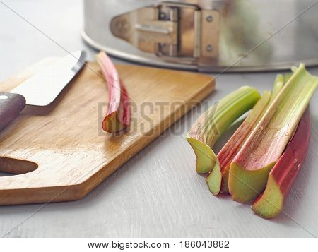 Cooking process. Home baking concept. Preparing rhubarb cake. Ripe rhubarb stems and some utensils  upon wooden board. Selective focus.