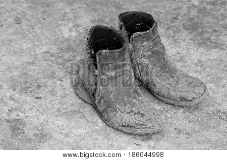 Pair of very dirty boots - black and white picture.