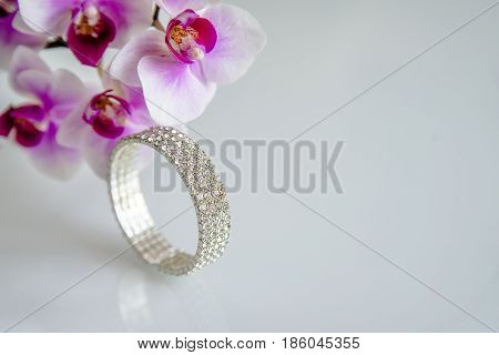 Zirconium bracelet lies on the background of purple orchids